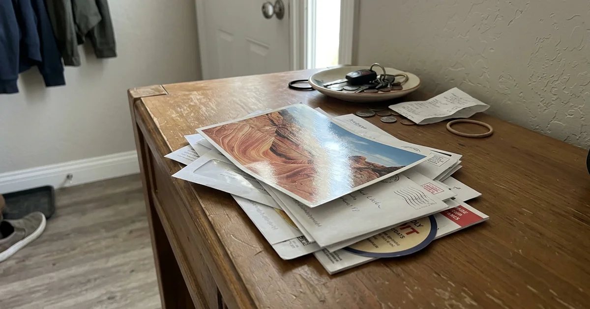 Oversized glossy postcard on top of a pile of letter mail