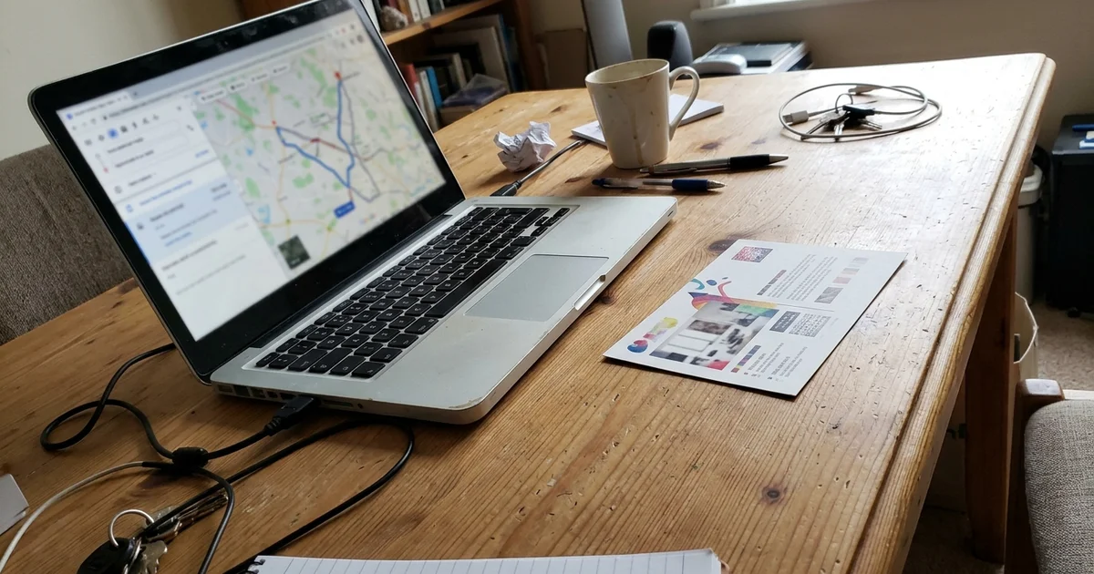 Route map on a laptop beside a printed postcard mockup