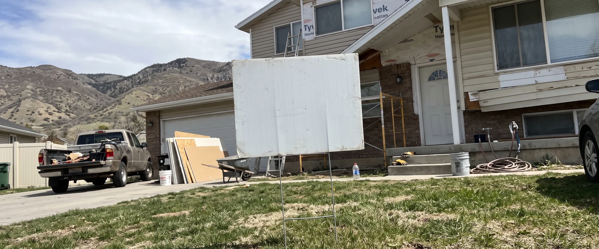 Yard sign on an H-stake in the front lawn of a home under renovation
