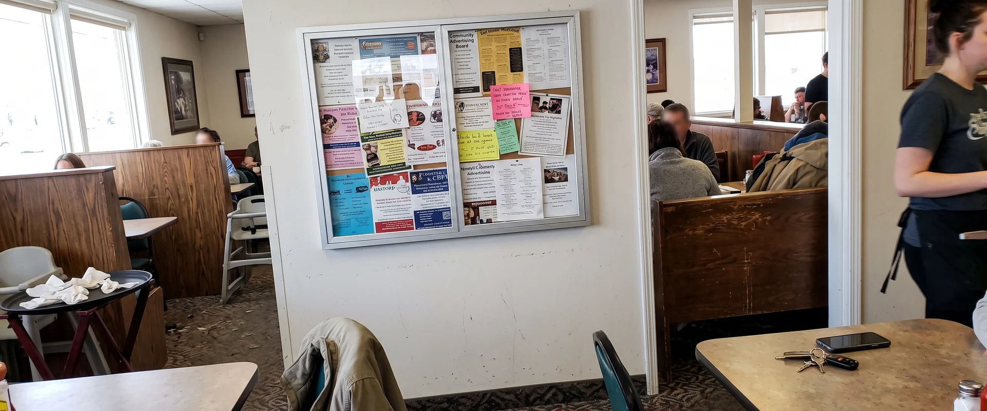 Community advertising board with local business ads on a busy restaurant wall