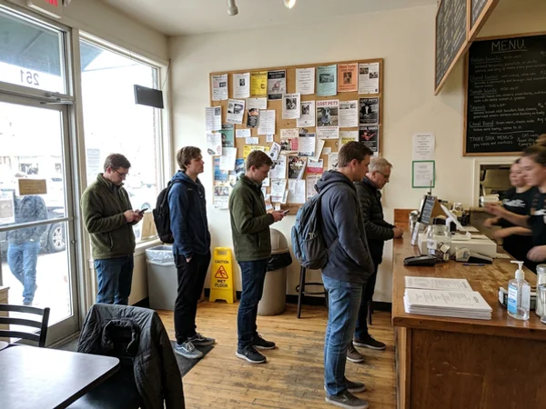 Customers in line near a community board