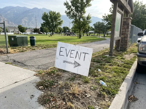 Event yard sign near a park entrance