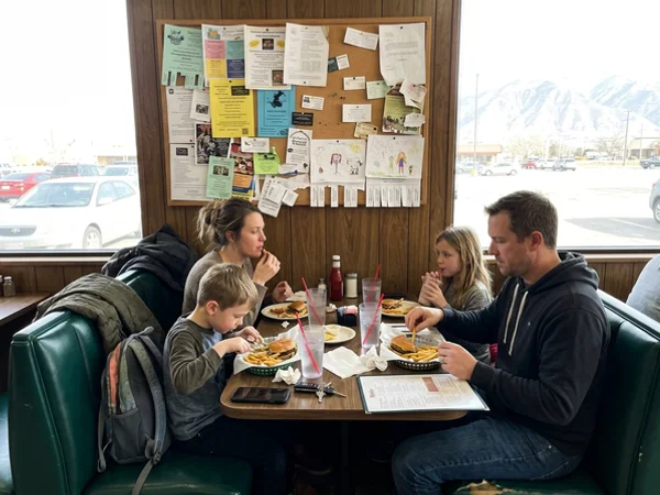 Diners at a booth with the community board on the wall
