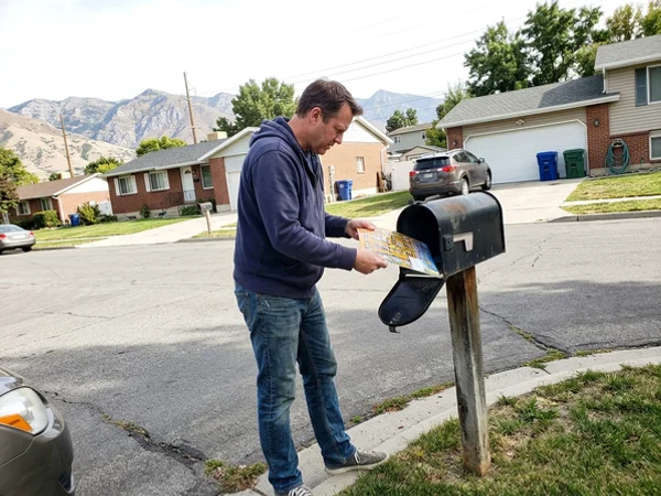 Homeowner pulling the postcard out of a curbside mailbox